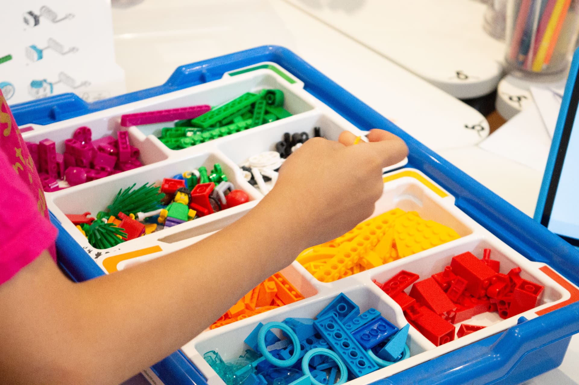 A child reaching into a colour-sorted robotics kit
