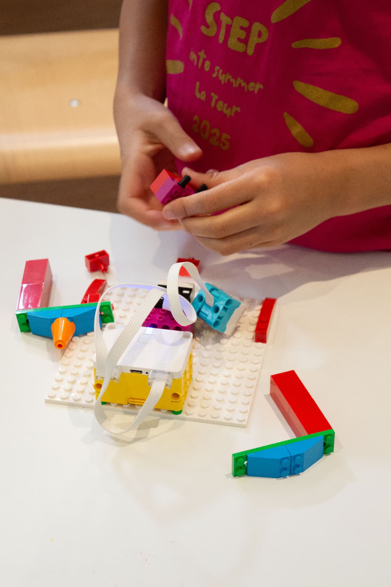 A child assembling a programmable robot on a building plate